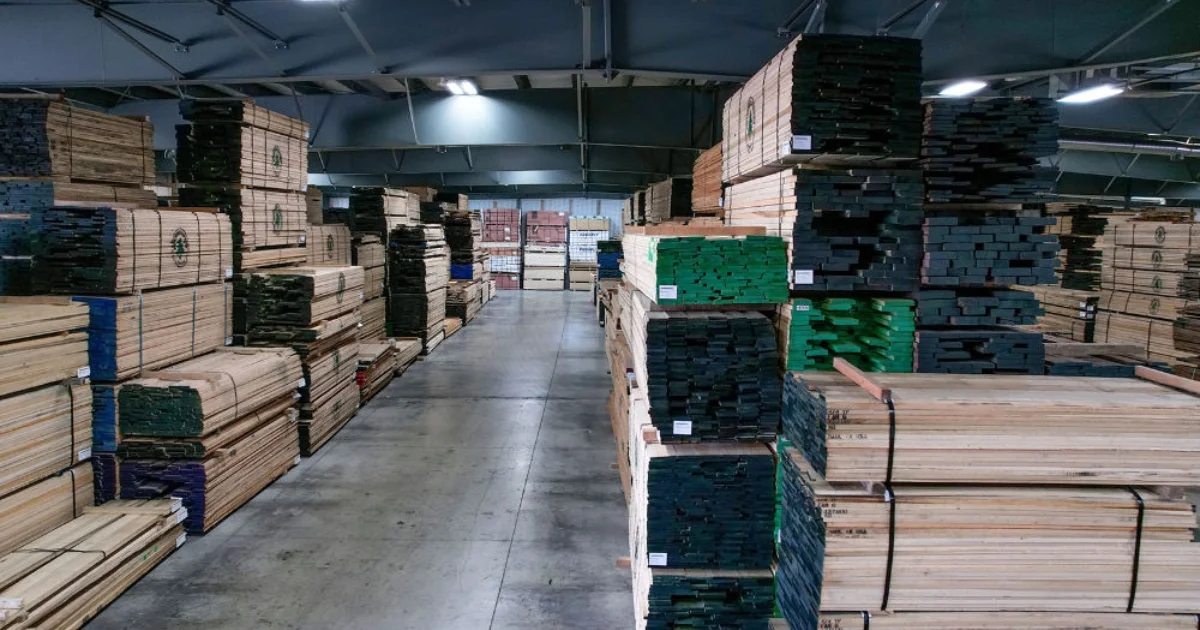Stacks of lumber stored in a large warehouse.